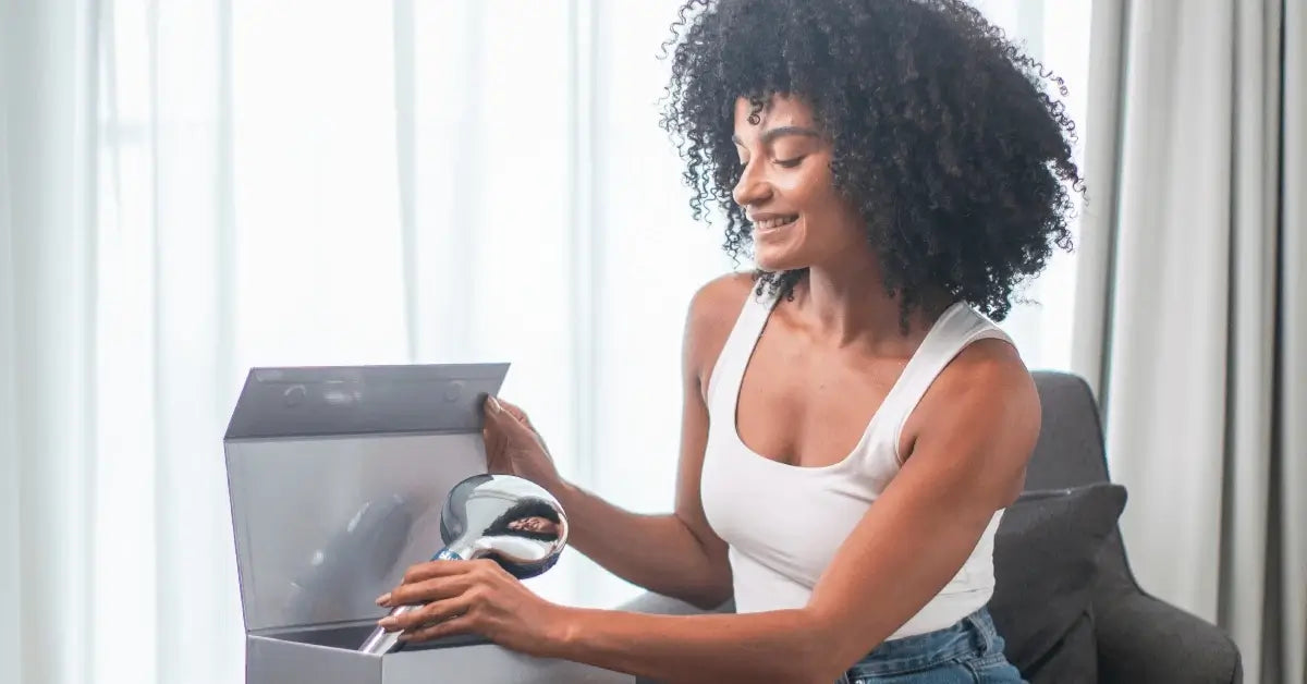 Woman with curly hair unboxing the blu Ionic Shower Filter handheld