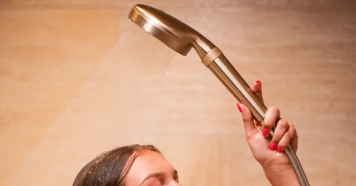 Woman holding the blu Ionic Shower Filter handheld in Matte Champagne