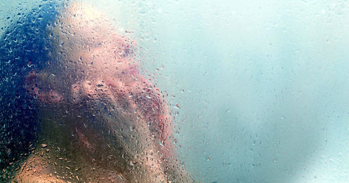 Woman showering behind a glass partition, blurred