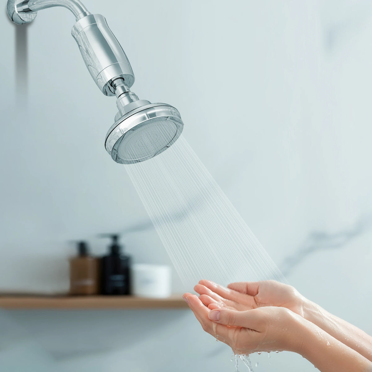 Hands cupped under a wall-mounted shower fitted with the blu NXT LVL Shower Softener